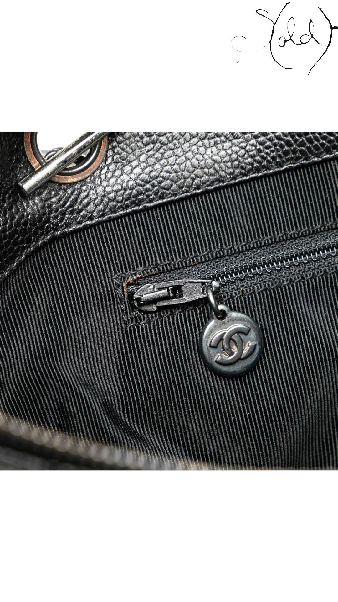 Sold Attire Chanel black caviar leather CC tote bag interior zipper with silver CC charm and silver hardware detail.