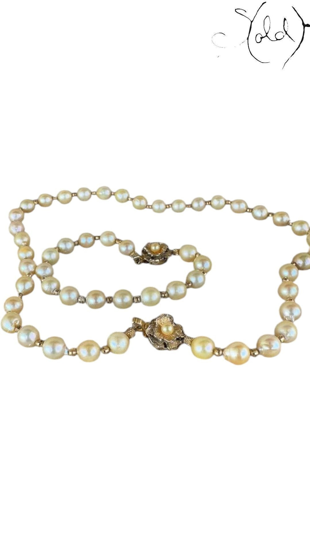 Sold Attire cream Akoya pearl necklace and bracelet set with decorative silver clasps on a patterned fabric background.