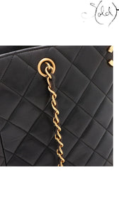 Sold Attire black quilted lambskin Chanel CC chain tote with gold-plated hardware and turn-lock closure.