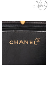 Sold Attire black lambskin Matelasse chain tote interior with gold Chanel logo and registered trademark symbol.