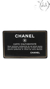 Sold Attire Chanel authenticity card, black with gold trim and text. Features Chanel logo and "Carte d'Authenticite" inscription.