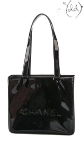 Sold Attire black patent leather tote bag with gold hardware and embossed Chanel logo. Early 2000s.