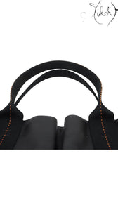 Sold Attire black Veau Derma calfskin Hermès Caravan Horizontal MM tote bag with orange contrast stitching and silver hardware.