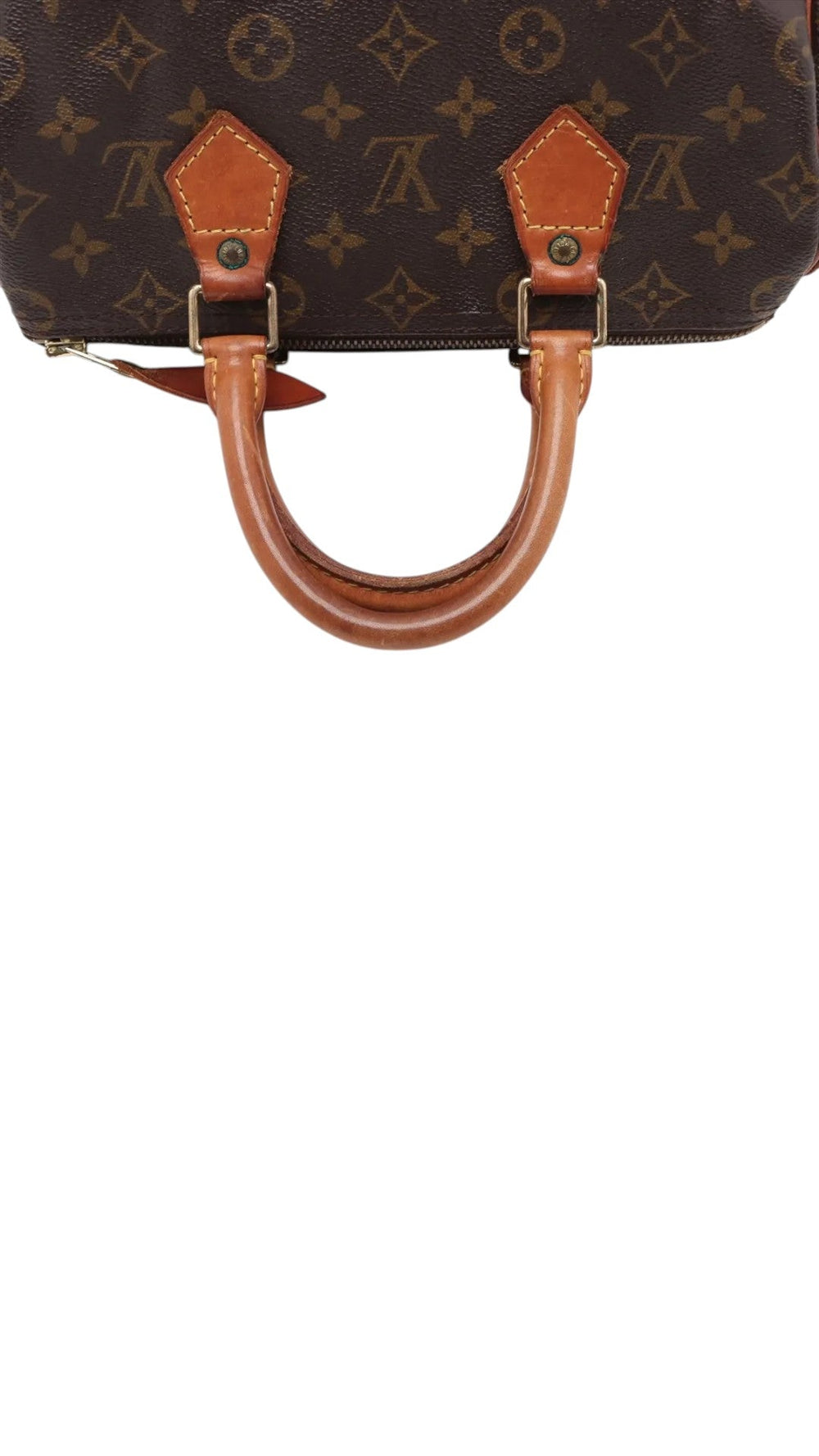 Sold Attire brown Louis Vuitton Monogram Speedy 25 canvas handbag with vachetta leather trim and brass hardware.