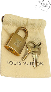 Sold Attire Louis Vuitton brass padlock and two keys resting on a small beige branded fabric pouch