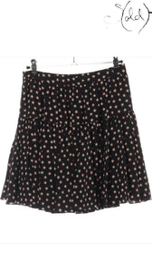 Sold Attire black silk twill mini skirt with a white and red star print, featuring a tiered, pleated design and a concealed back zip.