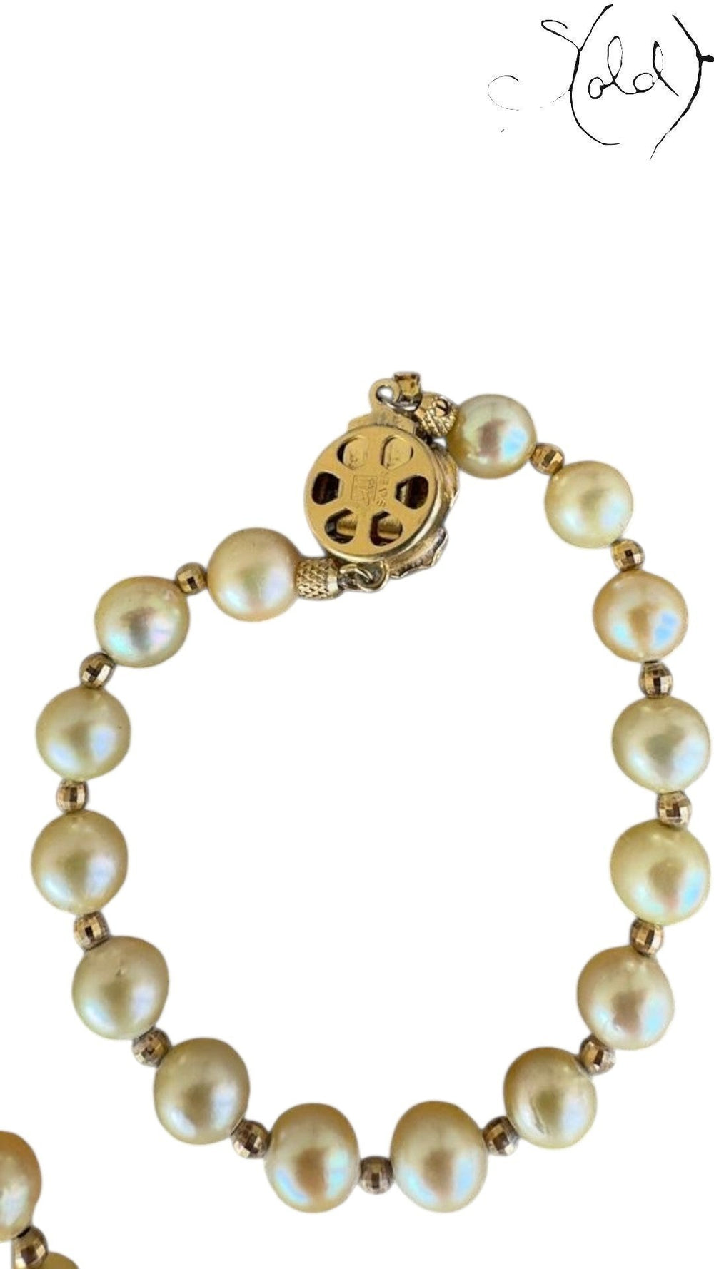 Sold Attire cream Akoya pearl bracelet with intricate silver clasp detail on a textured fabric background.