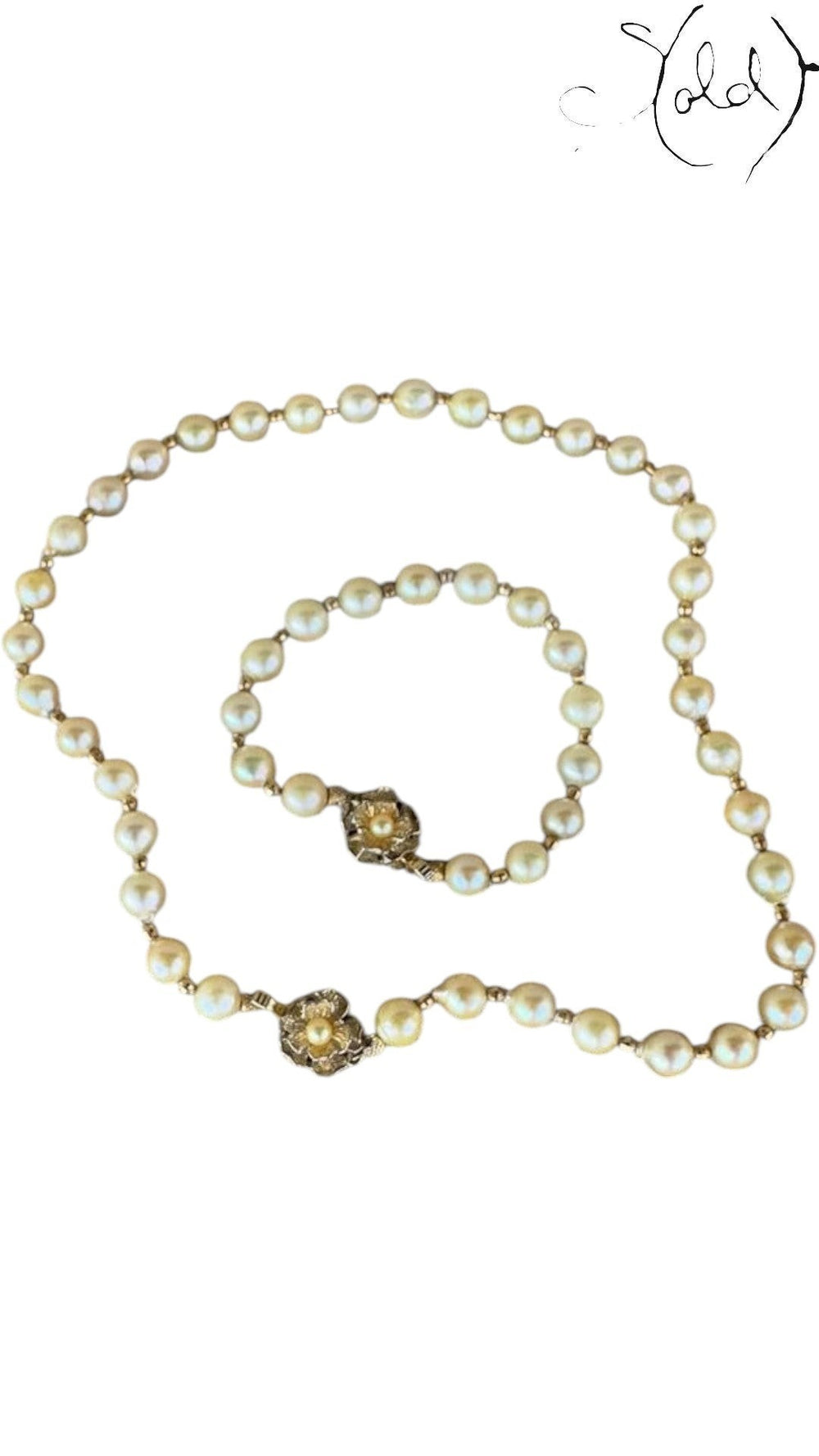 Sold Attire cream Akoya pearl necklace and bracelet set with decorative silver clasps on a patterned fabric background