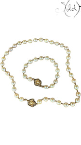 Sold Attire cream Akoya pearl necklace and bracelet set with decorative silver clasps on a patterned fabric background