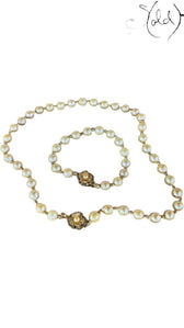 Sold Attire cream Akoya pearl necklace and bracelet set with decorative silver clasps on a patterned fabric background.